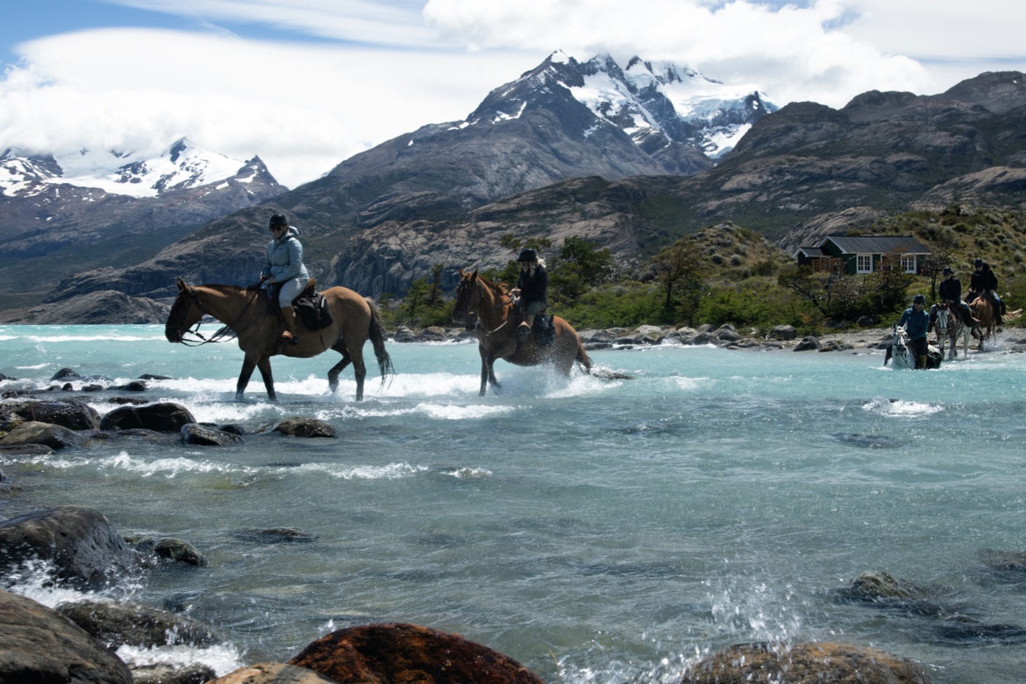 Horseback riding at Estancia Cristina through a Patagonian river surrounded by mountains near El Calafate.